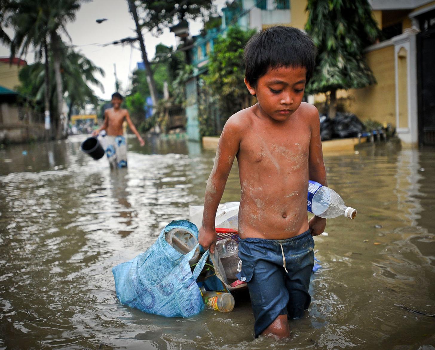 A boy drags possessions through the flooded streets of Manila in the aftermath of a typhoon.