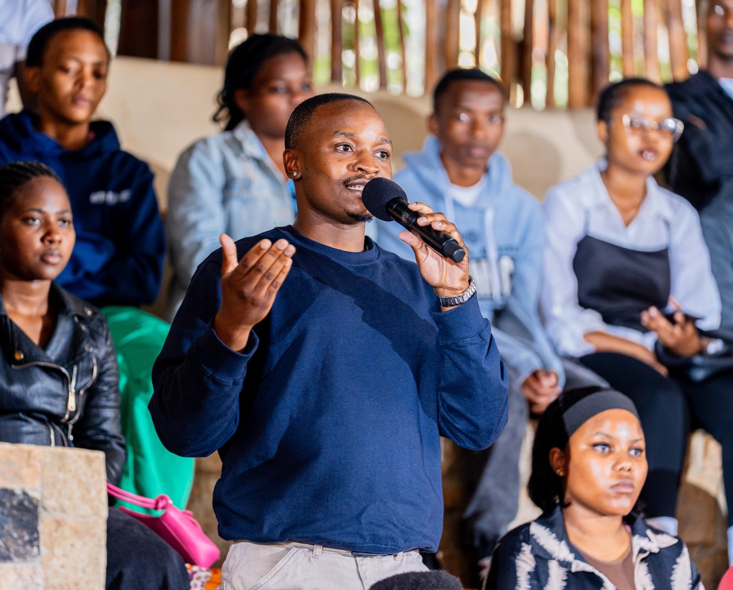 A young man holds a microphone to ask a question