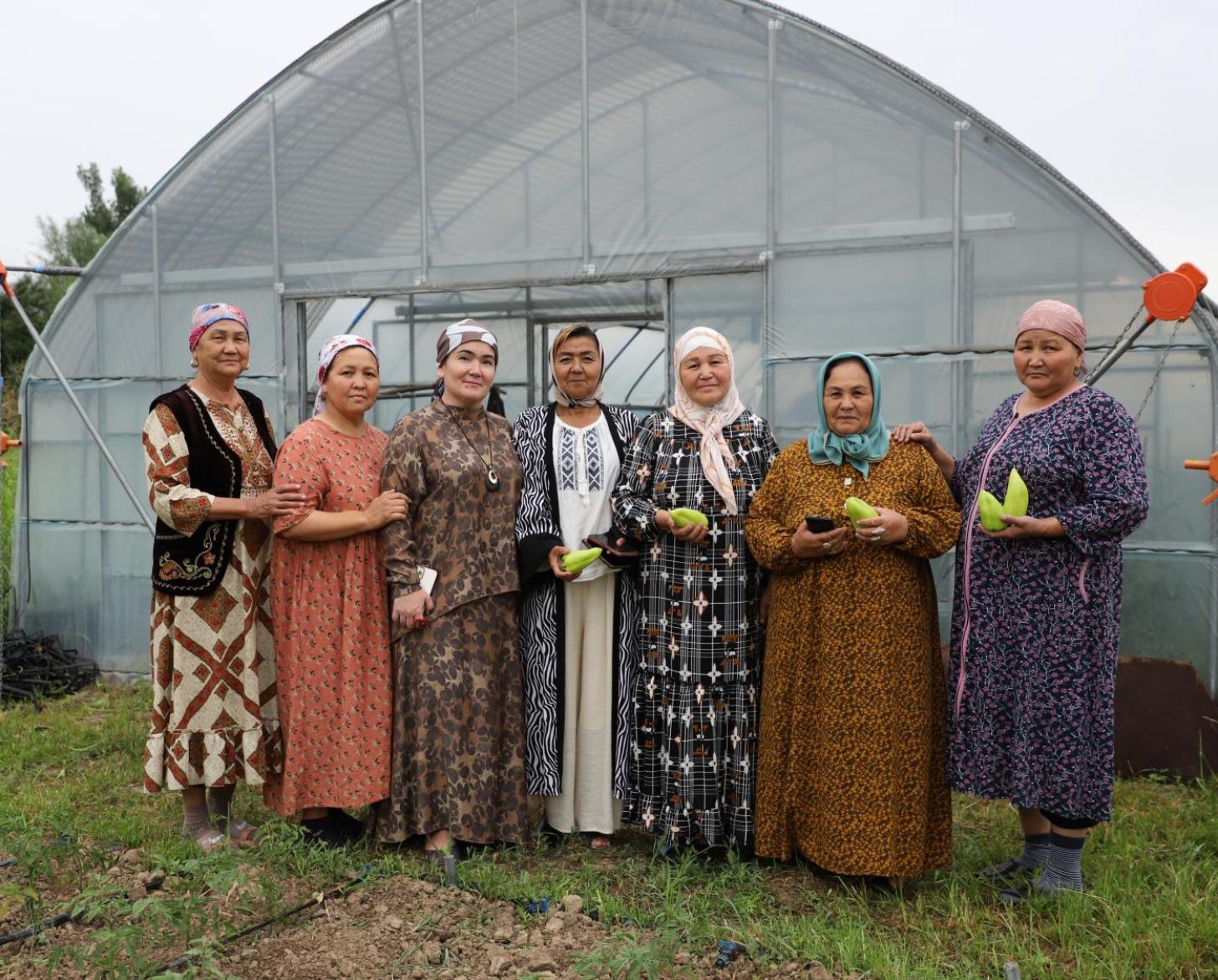 A group of women standing outdoors holding agricultural produce