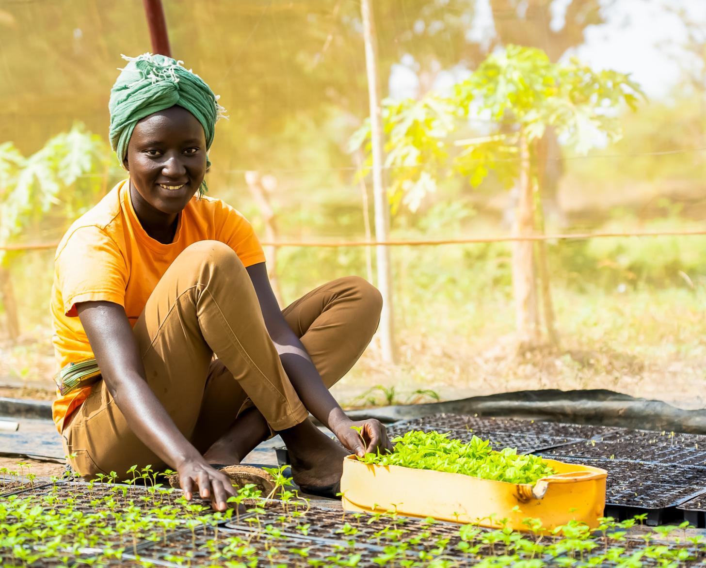 A woman in a yellow shirt sitting in a community garden
