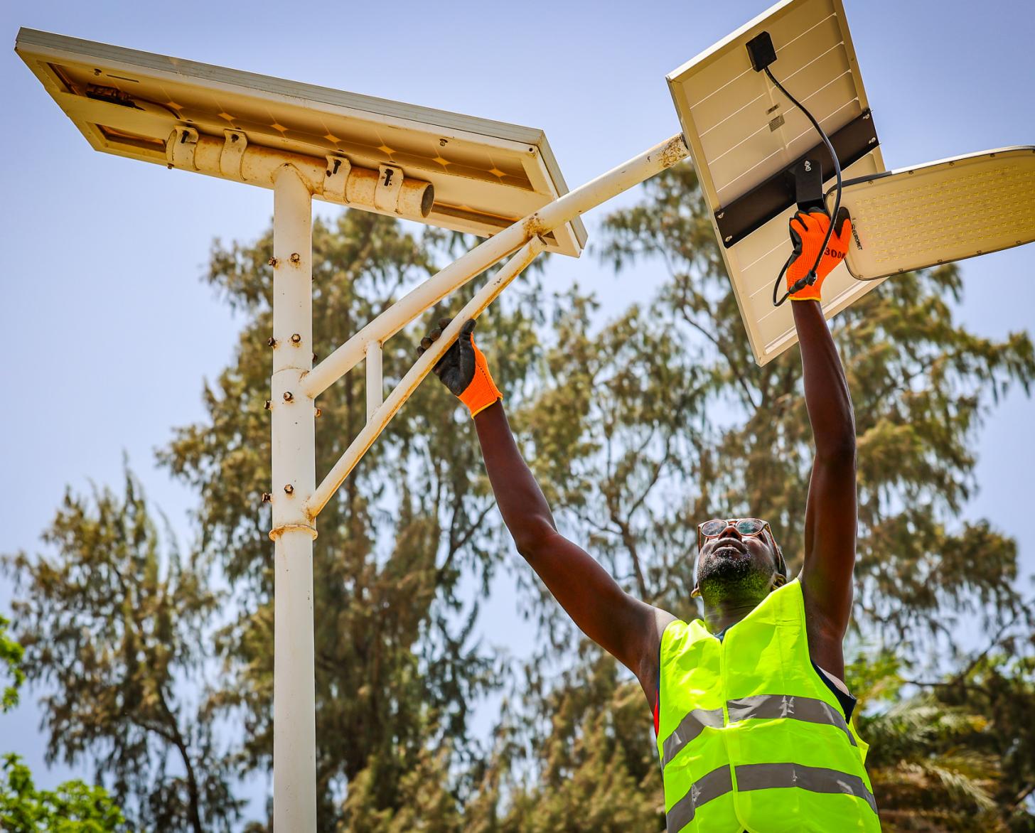 A man erects a pole with solar panels
