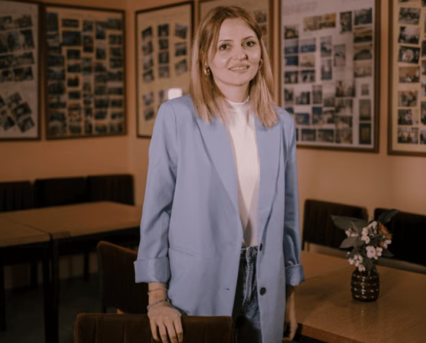 A young lady in business casual attire stands and smiles to the camera.