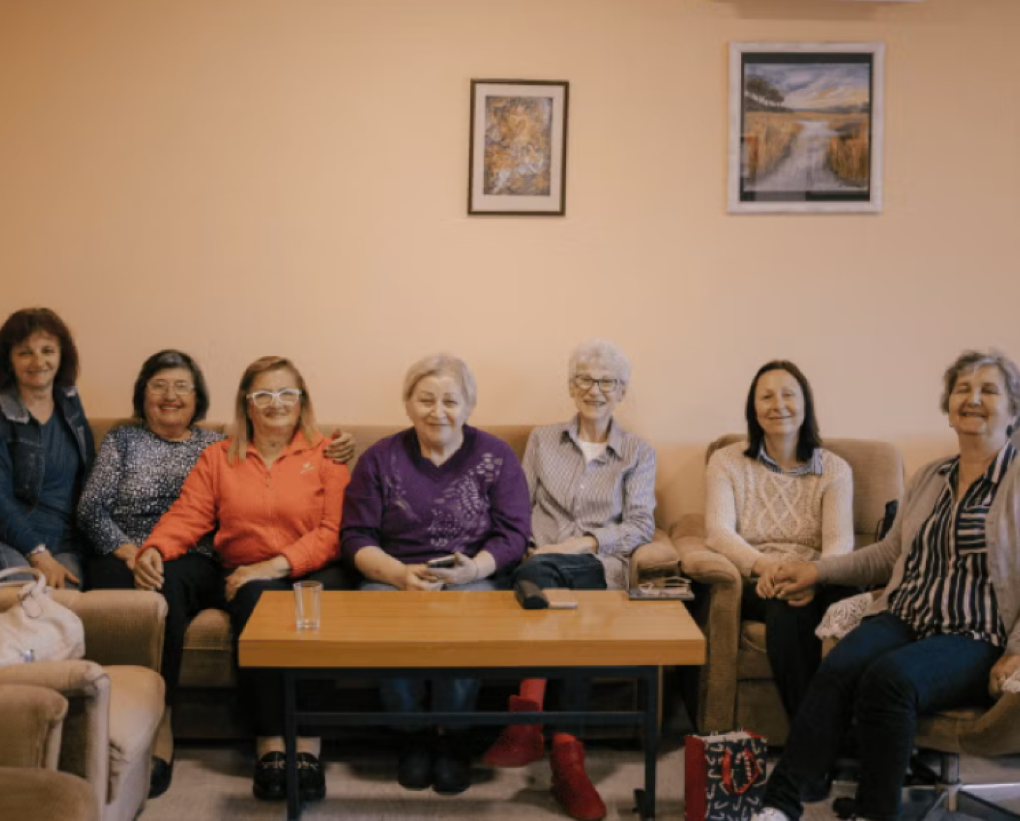 A group of pensioners are sitting together in a sofa.