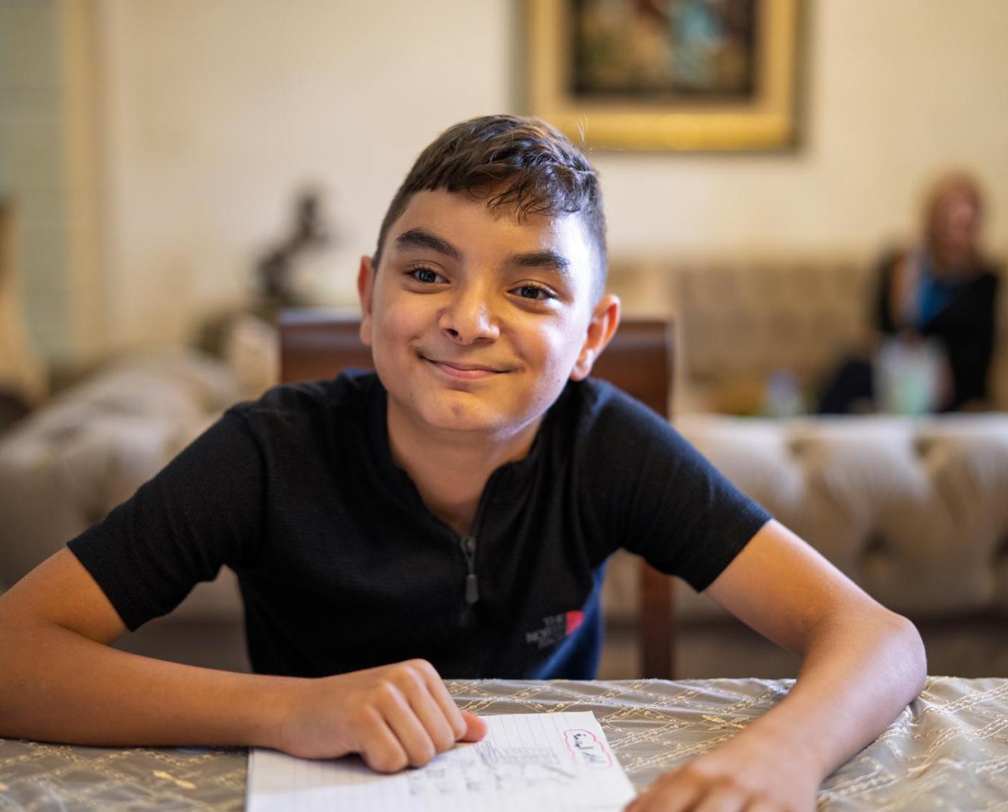 A young boy in Lebanon sits at a table.