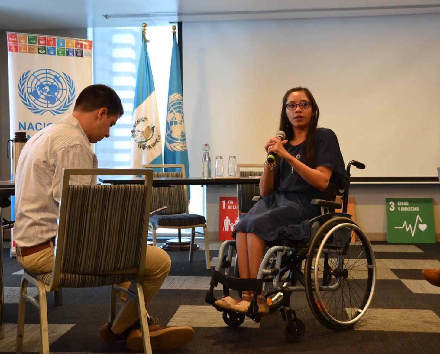 A female disability-inclusion leader in Guatemala speaks with a high-level UN official at a workshop.