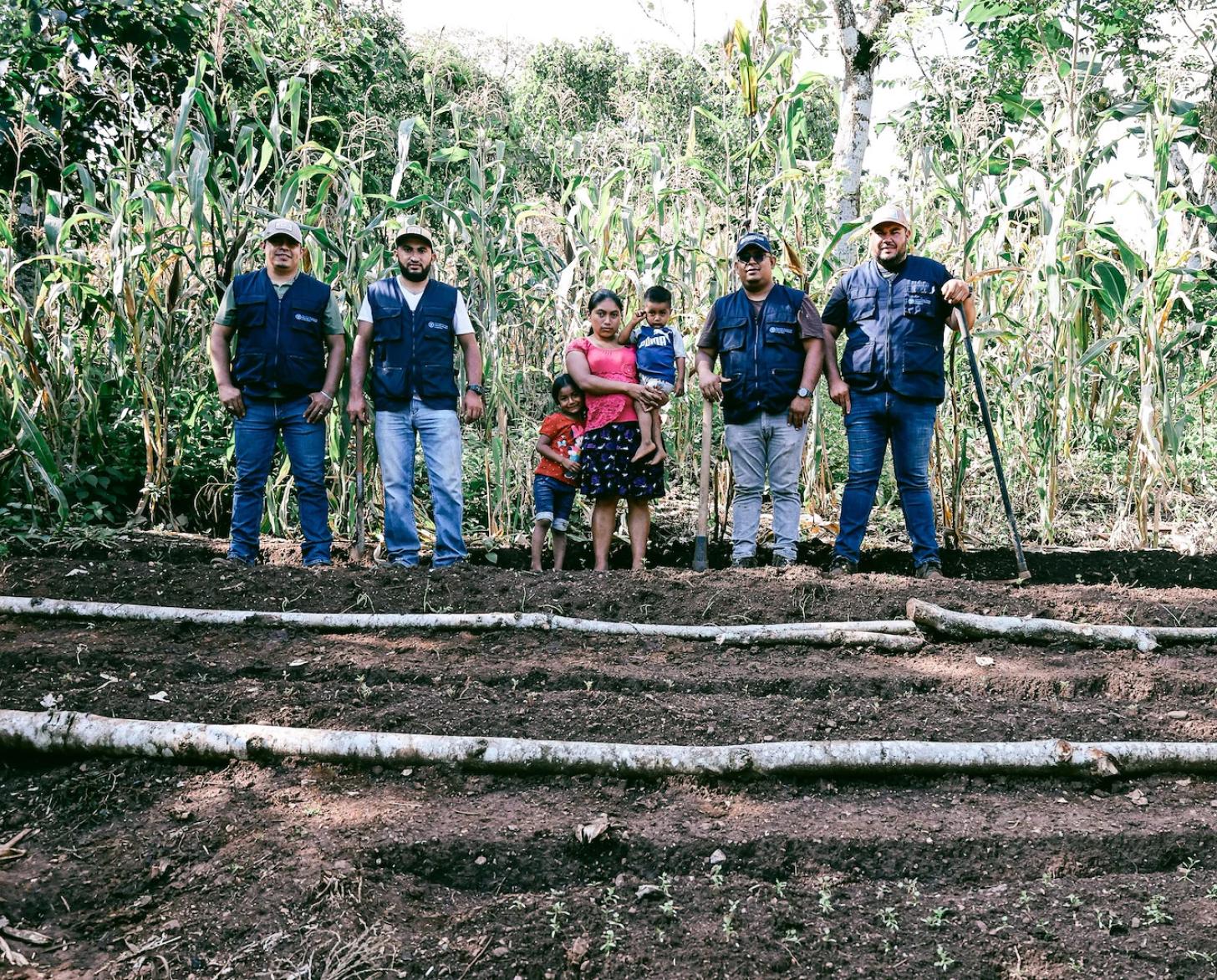 UN staff stand in a field with a local Guatemalan female farmer.