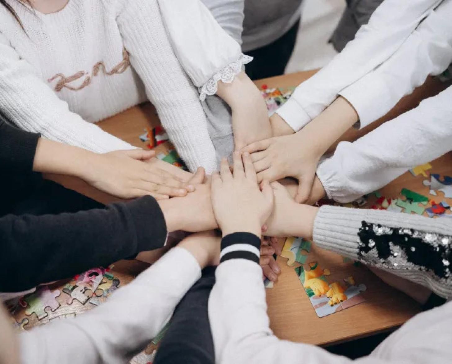 A group of girls in Moldova join their hands in a circle.