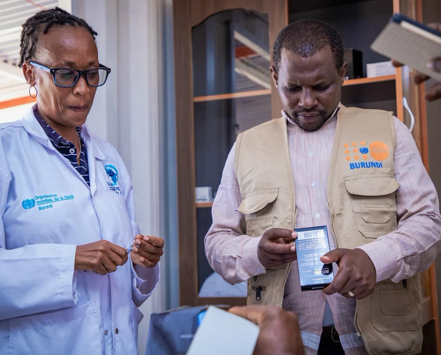 A female and male health worker in Burundi examine a box of medications.