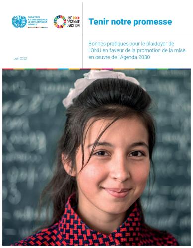 Portrait d'une jeune fille brune aux cheveux attachés, souriant à la caméra devant un tableau de classe.