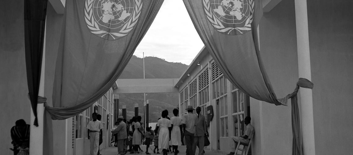 Haiti Cover showing several people walking away from an entrance with two United Nations flags.