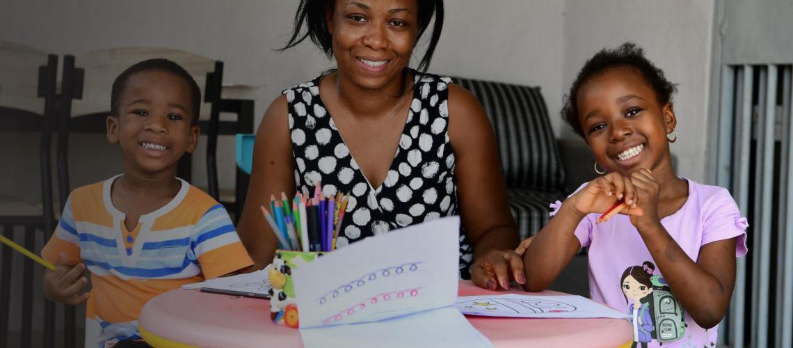  A mother helps her children to draw, at their home in Abidjan.