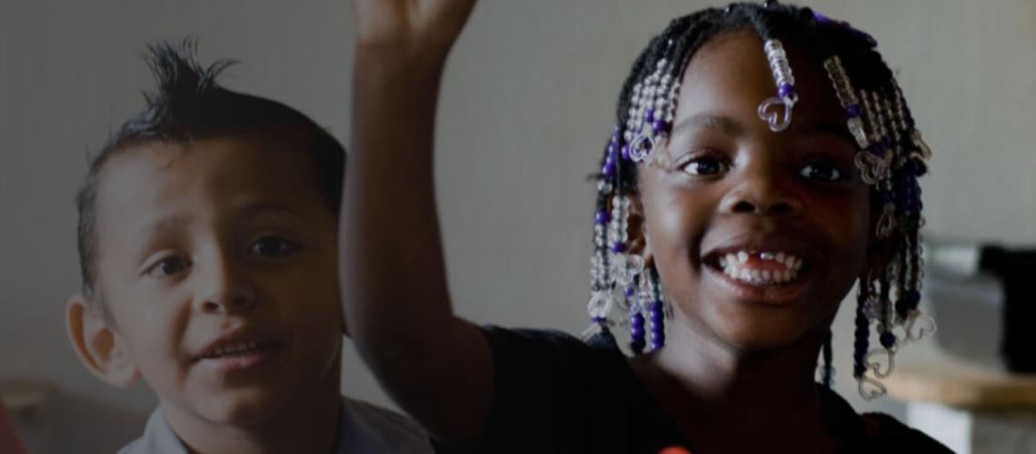 A little boy and girl enthusiastically smile at the camera.
