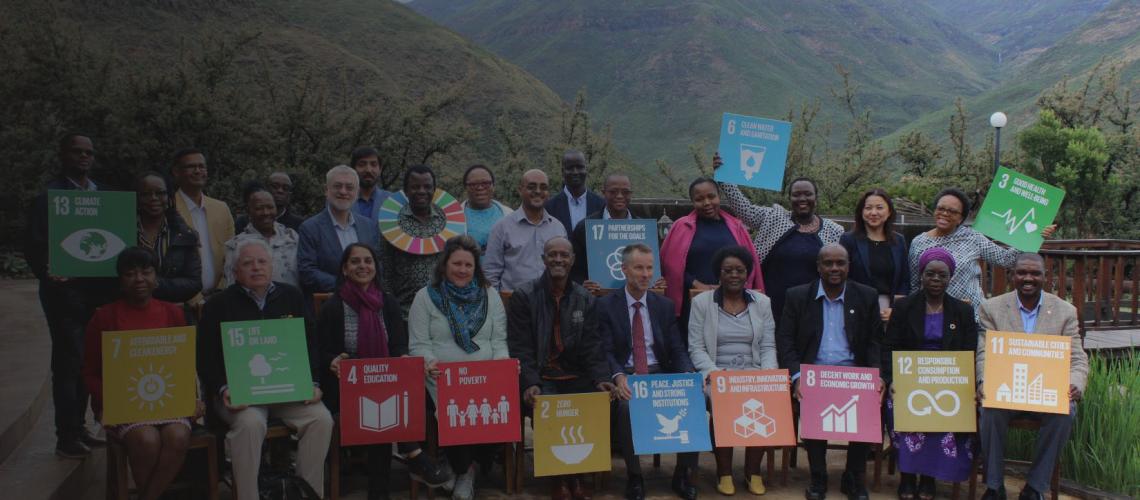 A photo of the UN Country Team staff holding SDG signs with a mountainous background.  