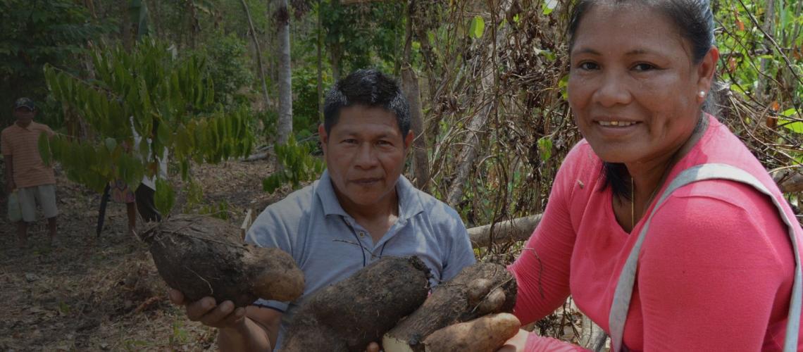 An indigenous man and women proudly show us their vegetation.