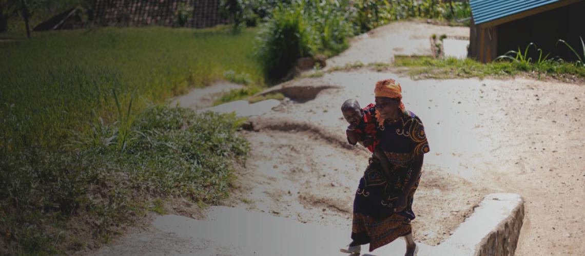 A woman carries a baby up cement stairs.