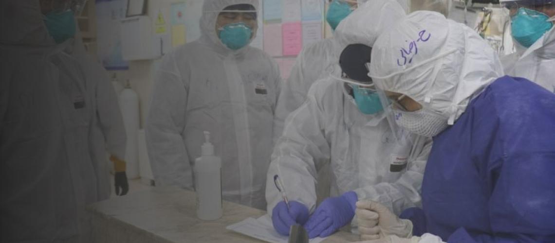 UN staff and healthcare workers in a medical facility complete documents while wearing full protective gear.
