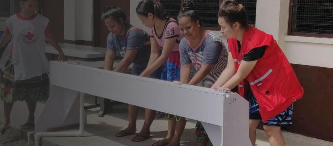 Women are instructed on proper and safe handwashing at a handwashing station.