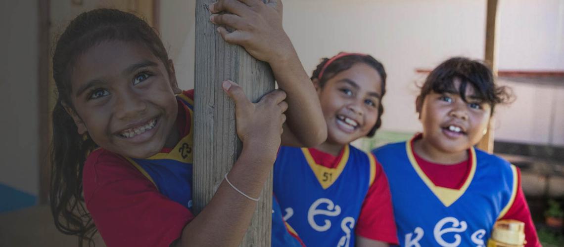Three young girls smile cheerfully at the camera.