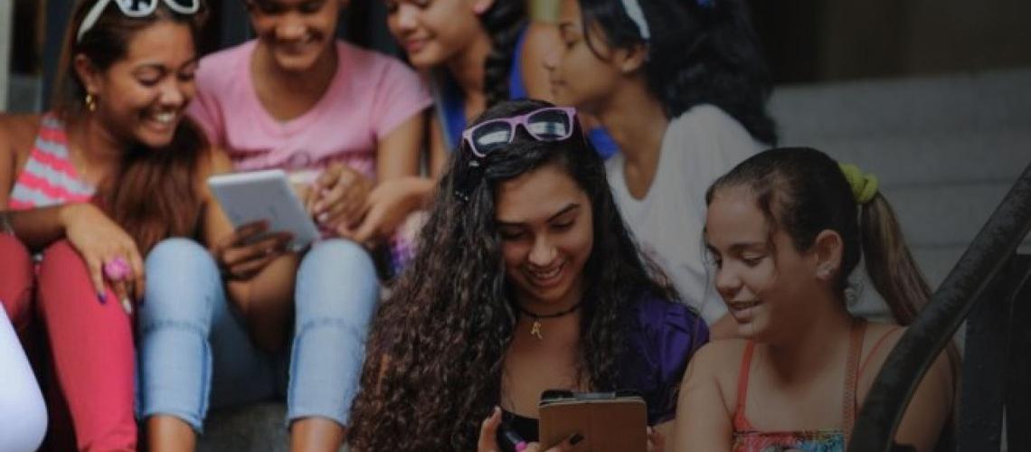 تجلس الشابات معًا على درج وينظرن بفرح إلى الأجهزة اللوحية.