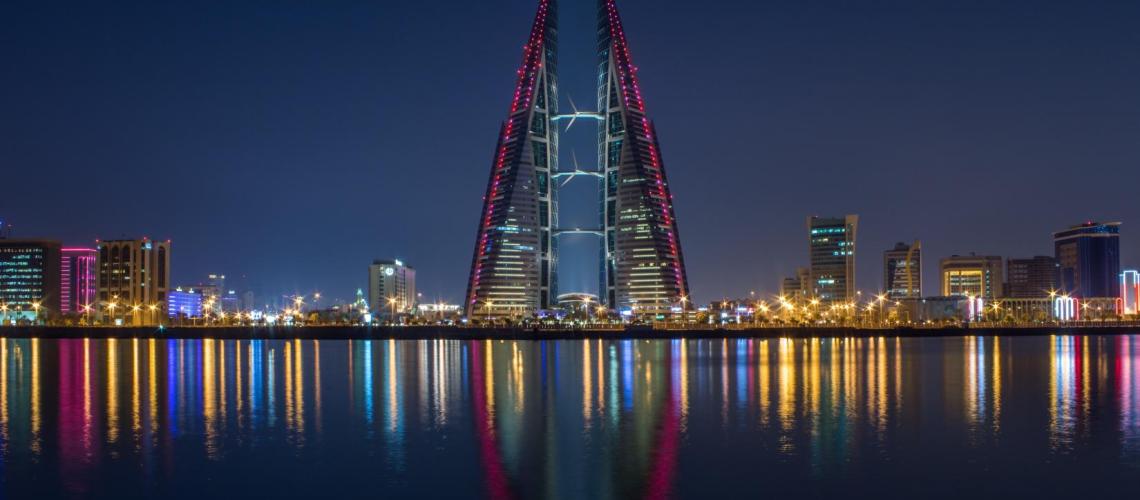 An image of a colorful skyline at night reflecting into the water. 