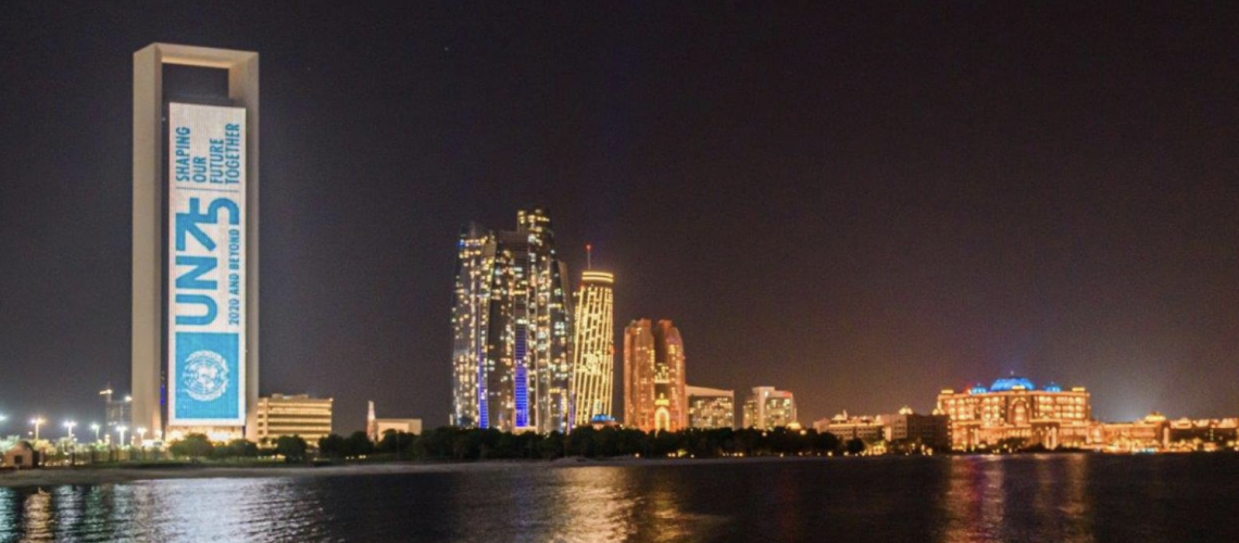 A skyline view near a body of water with a large sign celebrating 75 years of the United Nations is displayed on a building.. 
