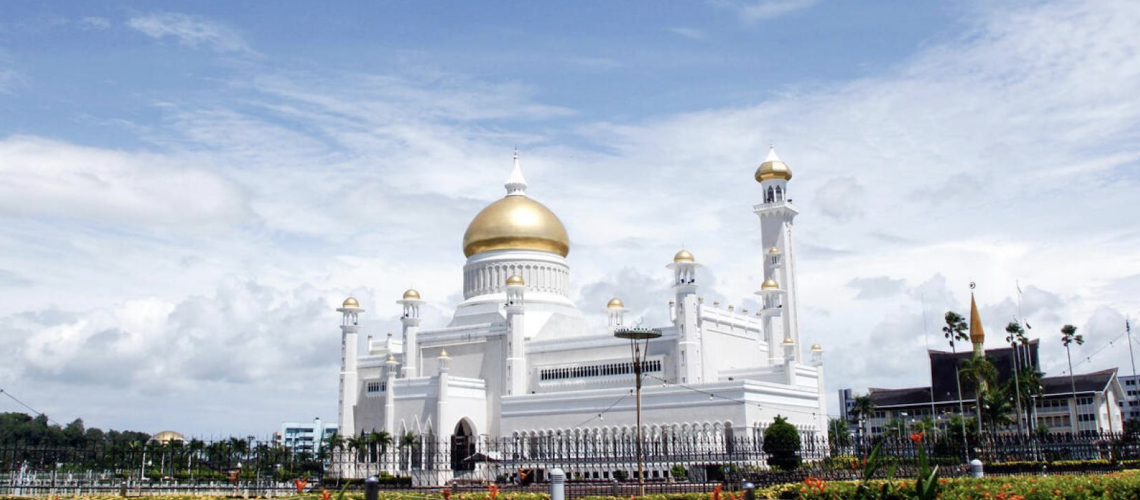 An image of a white temple with a gold roof on a beautiful day.
