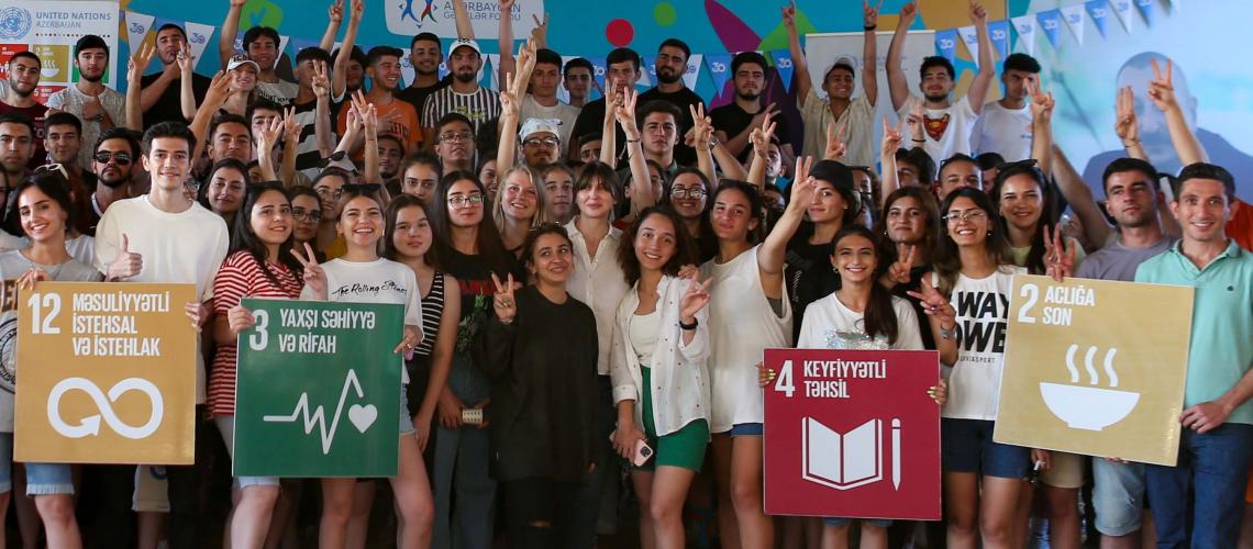 A big group of kids hold SDG signs and stand for a group photo.