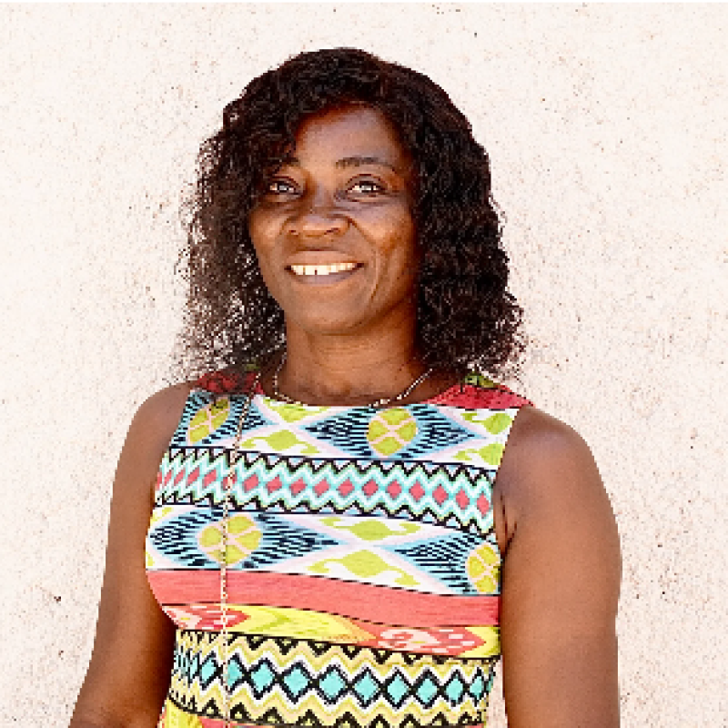 Une femme portant une haut bariolé sans manches regarde l'objectif en souriant. 