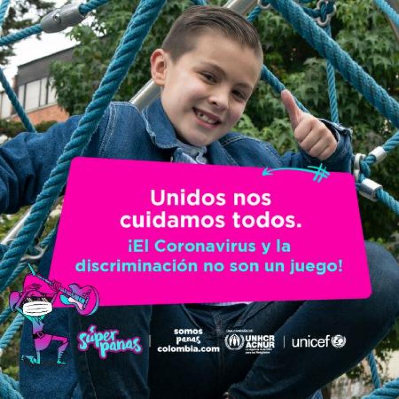 一个小男孩微笑着竖起大拇指，坐在操场上。